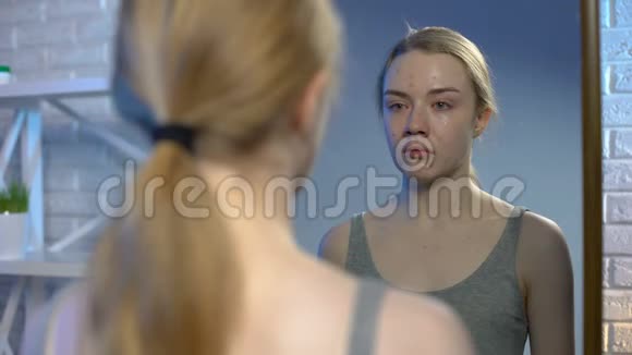 沮丧的年轻女子在镜子里看着脸上青春痘视频的预览图