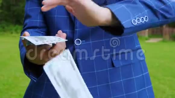 一个年轻的商人穿着一套蓝色的格子西装用手扔钱视频的预览图