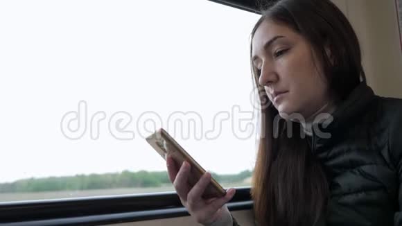 年轻女子正在看智能手机上的火车旅行视频的预览图