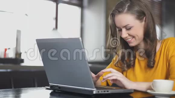 微笑的女人在咖啡馆的笔记本电脑上聊天用交友网站结识朋友视频的预览图