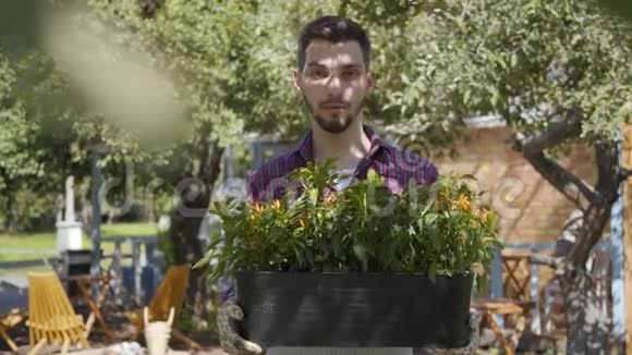 一幅可爱的胡子农夫手捧一盆花的画像看着相机微笑地站在老人面前视频的预览图