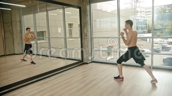一个运动员站在画室里对着镜子训练他的拳击视频的预览图