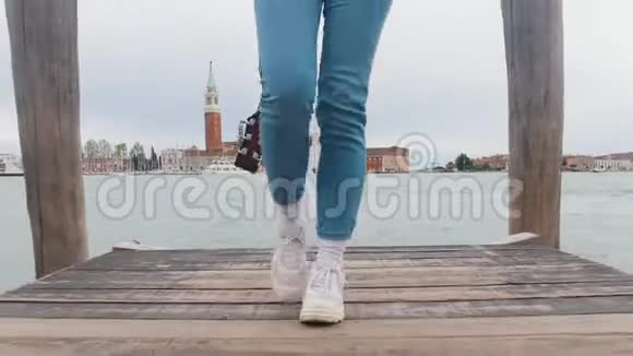 一位年轻女子背着吉他在码头上向前走有摄像头跟踪她视频的预览图