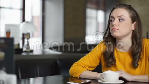 女人紧张地在咖啡馆里等着检查智能手机然后离开糟糕的约会视频的预览图