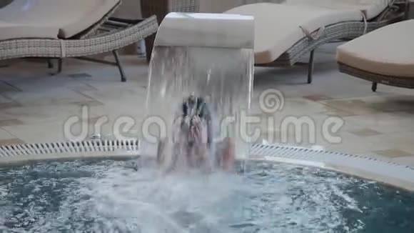 美丽的女孩在室内游泳池的瀑布下游泳视频的预览图