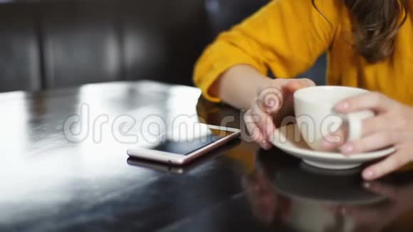 伤心的女人在咖啡馆里检查电话等待男朋友吵架后的电话视频的预览图