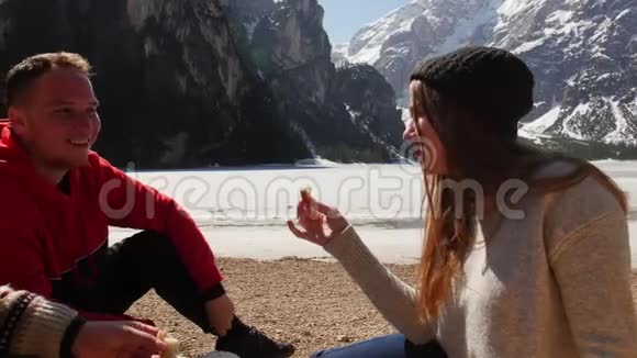 年轻人旅行三个朋友在海岸野餐吃三明治视频的预览图