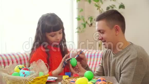爸爸和女儿用蓝色颜料在鸡蛋上画画然后开始互相弄脏对方脸爸爸用刷子弄脏了视频的预览图