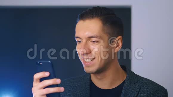 年轻英俊的商人使用他的智能手机在办公室背景看相机和微笑商务视频的预览图