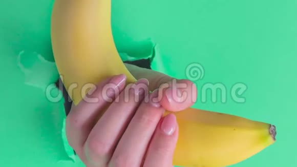 一个女人手里拿着一根香蕉插在破绿纸上的一个洞里视频的预览图