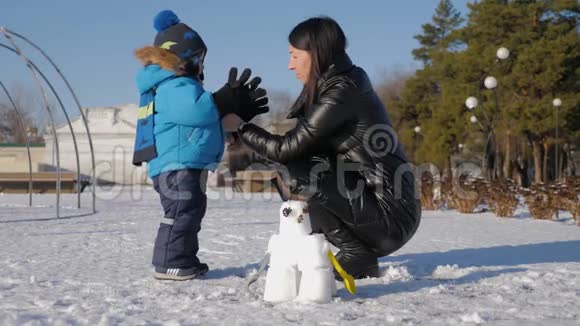 小男孩和他妈妈在雪地公园玩得很开心快乐的家庭在冬天玩雪活跃的冬季游戏视频的预览图