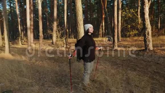 一个带着跋涉杆的女孩站在森林的中央视频的预览图