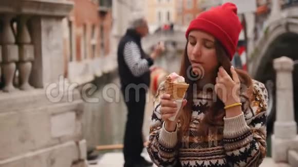 站在水道背景上吃冰淇淋的年轻女子视频的预览图