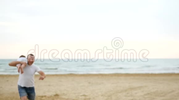 一个男人抱着一个孩子慢悠悠地沿着沙滩奔跑视频的预览图