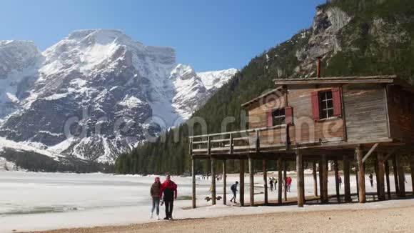 年轻夫妇在旅行手牵着手走在寒冷的海岸上背景上山的美丽景色视频的预览图