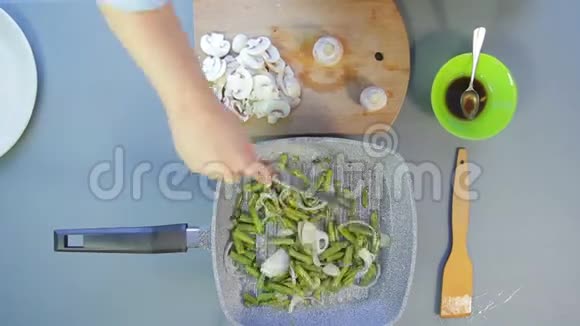 一个女人在平底锅里拌青豆用刀切香菇然后在豆子里加入豆子时间圈视频的预览图