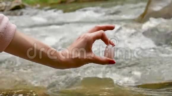 雌性手拿着玫瑰石英水晶玉蛋在河底女性健康与自然观念的统一视频的预览图