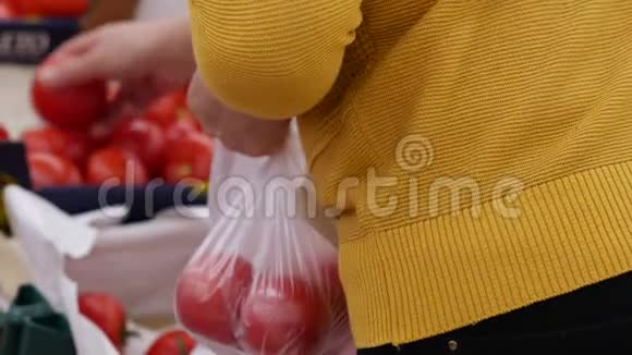 超市的购物者选择新鲜的西红柿穿黄色上衣的女人穿着h视频的预览图