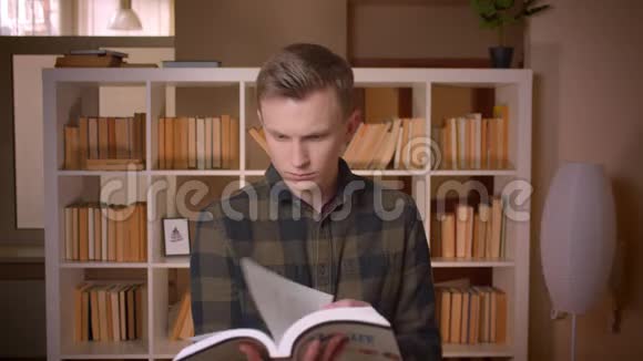 在大学里年轻迷人的白种人男学生正在看一本书看着摄像机开心地笑着视频的预览图