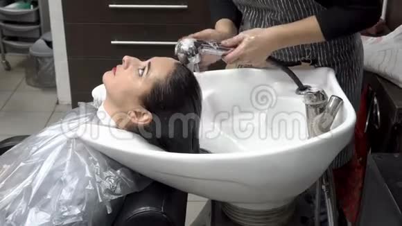 理发师在理发和染发后理发店里给这位妇女洗头头发护理一般视频的预览图