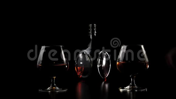 豪华白兰地手拿着两个杯子中的一个和金色干邑从一个黑色的桌子在黑色的背景下白兰地白兰地视频的预览图