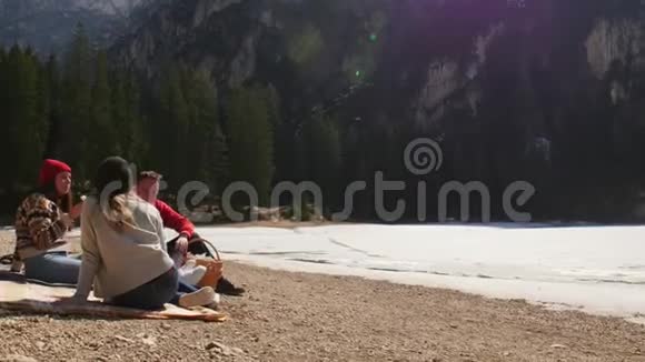 年轻人旅行朋友们在海岸野餐在山上吃三明治视频的预览图