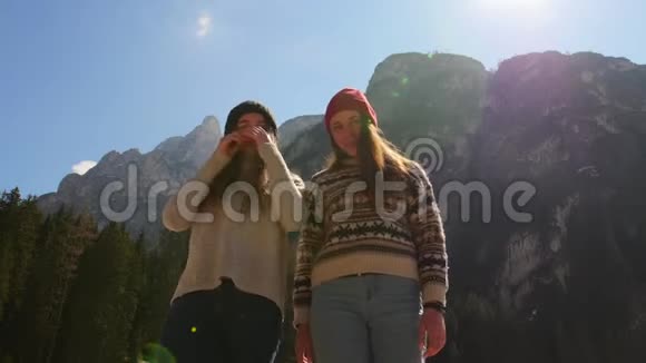 年轻人旅行两个年轻的女人站在一座山的背景上摆着姿势视频的预览图