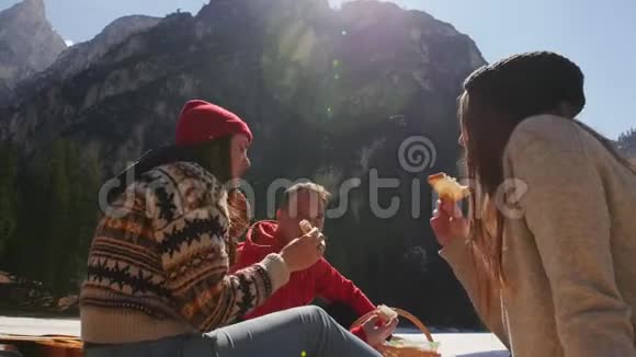 年轻人旅行去野餐的朋友坐在海岸边吃面包视频的预览图
