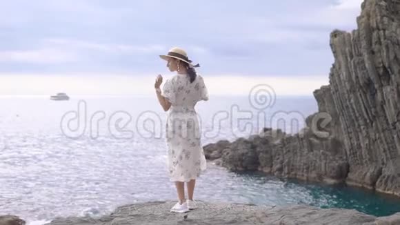 漂亮的意大利女人白天站在石海岸边转着镜头摆姿势视频的预览图