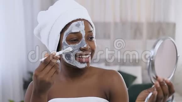 美国黑人英俊女子的肖像头上有毛巾半边脸上涂着黏土面具化妆视频的预览图