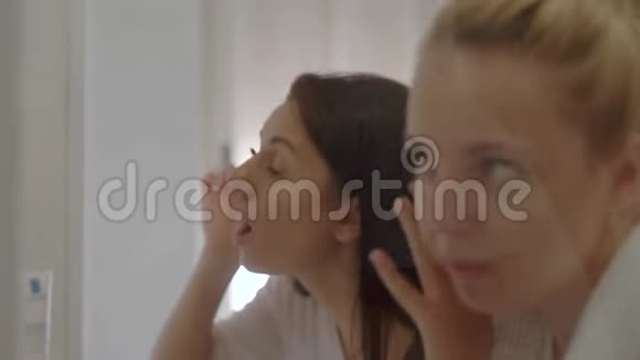两个年轻漂亮的女人正在浴室里准备新的一天化妆和护肤视频的预览图
