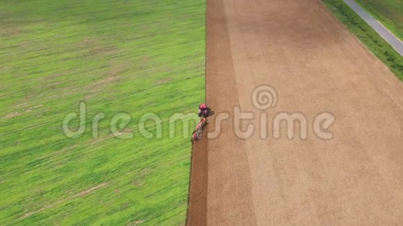 红拖拉机耕耘一片绿田以增加收获空中作业视频的预览图
