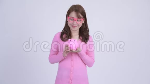 年轻快乐的亚洲书呆子女人拿着储蓄罐竖起大拇指视频的预览图
