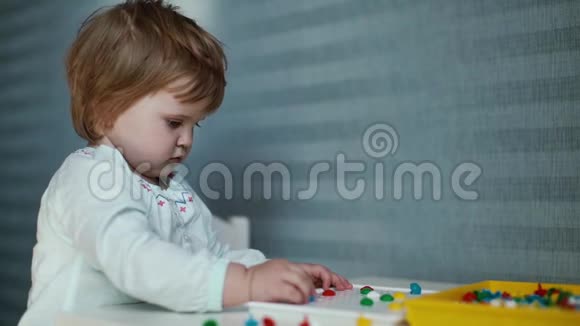 小女孩坐在儿童桌前微笑着慢慢地收集一幅马赛克视频的预览图