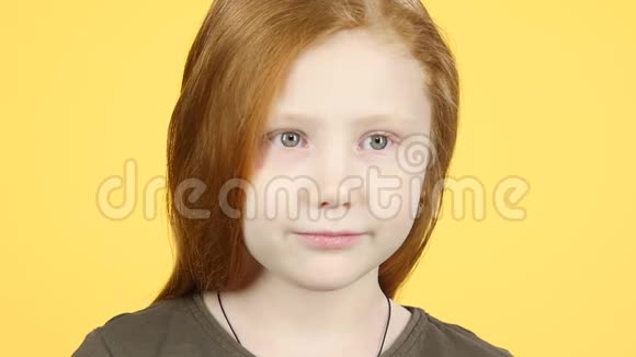 特写红发儿童对着黄色背景的镜头微笑慢动作视频的预览图