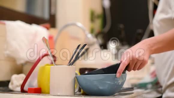 一个女人从一堆脏盘子里拿出一个盘子洗了它把重点放在有脏盘子的前台视频的预览图