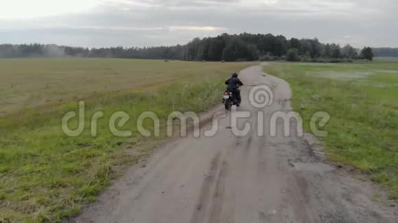一个年轻的摩托车手身穿黑色防护服头戴头盔在一个农村骑着后轮滑视频的预览图