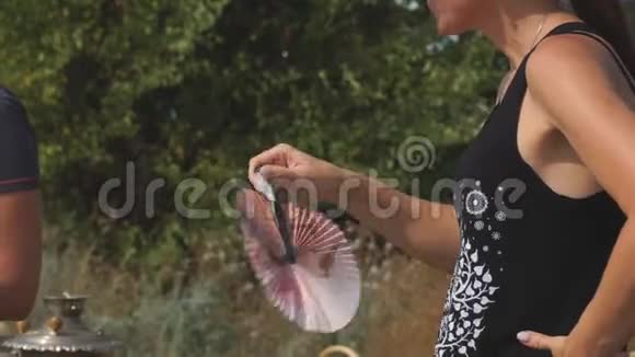 女孩在炎热的日子里用白色的扇子扇自己视频的预览图