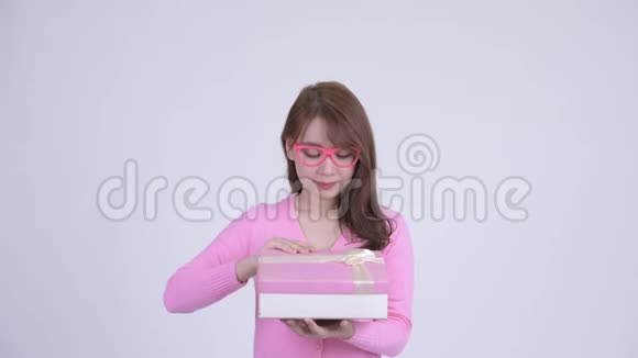 年轻快乐的亚洲书呆子女人打开礼物盒看上去很惊讶视频的预览图