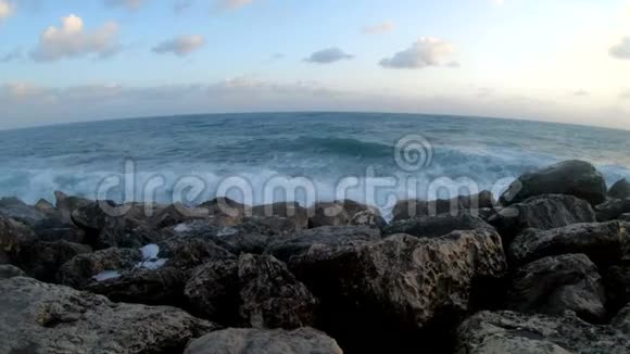 日落时分海浪拍打在岩石海滩上视频的预览图