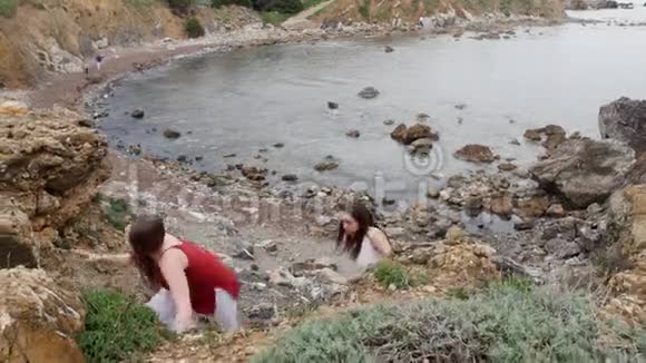 两个年轻的女人从海岸岩石墙视频的预览图
