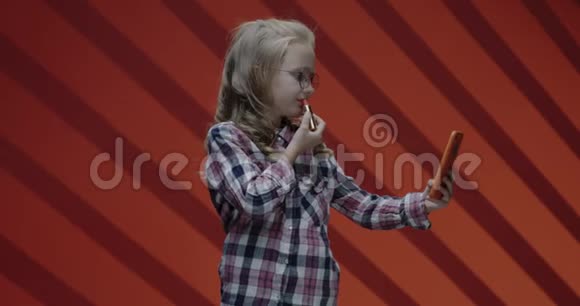 女孩一边涂口红一边看智能手机视频的预览图