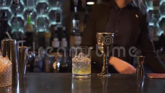一位棕色长发的酒保女孩将柠檬汁挤在一杯加冰的鸡尾酒里并将其放在独一无二的金属碗里视频的预览图