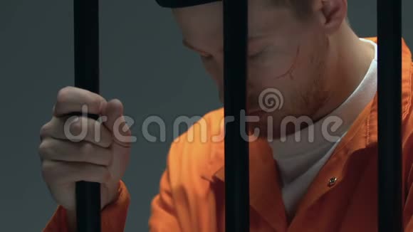 令人不安的囚犯脸上有伤疤手里拿着囚牢对犯罪感到遗憾视频的预览图