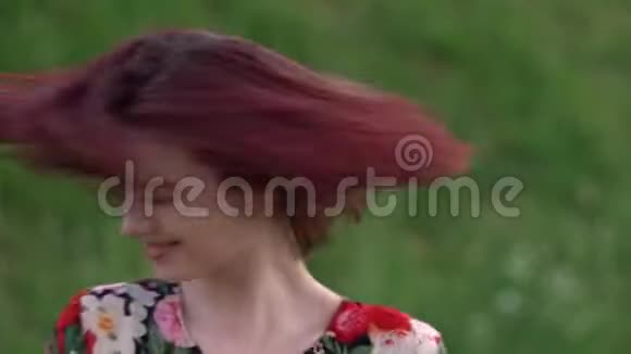 美丽的女孩摇着红头发的头微笑着看着摄像机视频的预览图