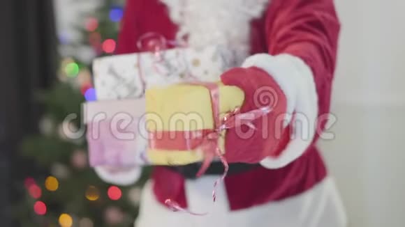 穿着圣诞老人服装的面目全非的人在新年树前送礼物他拿着礼物视频的预览图