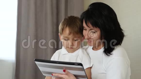 妈妈和她的孩子在家里玩平板电脑玩和看动画片玩电子游戏使用视频的预览图