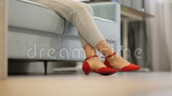 女人坐在沙发上穿着漂亮的红鞋坐在木地板上视频的预览图