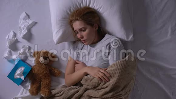 沮丧的女人在床上哭泣拥抱泰迪熊遭受流产视频的预览图