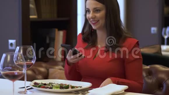 优雅微笑的女士坐在现代餐厅现代女性在豪华餐厅为自己的食物拍照视频的预览图
